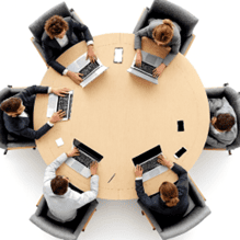 Ylhäältä kuvattu tilanne, jossa kuusi liiketoiminnan ammattilaista istuu pyöreän puupöydän ääressä kannettavien tietokoneiden kanssa. Pöydällä on myös älypuhelimia, muistilehtiö ja kynä. Kuva kuvastaa Stradigon Kapteeniprosessia: säännöllisiä, rytmitettyjä kokouksia, joissa tiimien kapteenit seuraavat strategian etenemistä, jakavat tietoa ja varmistavat yhteispelin. Digitaalinen näkymä tukee päätöksentekoa reaaliajassa, ja prosessi pitää strategian elävänä arjessa – ilman raskasta raportointia.